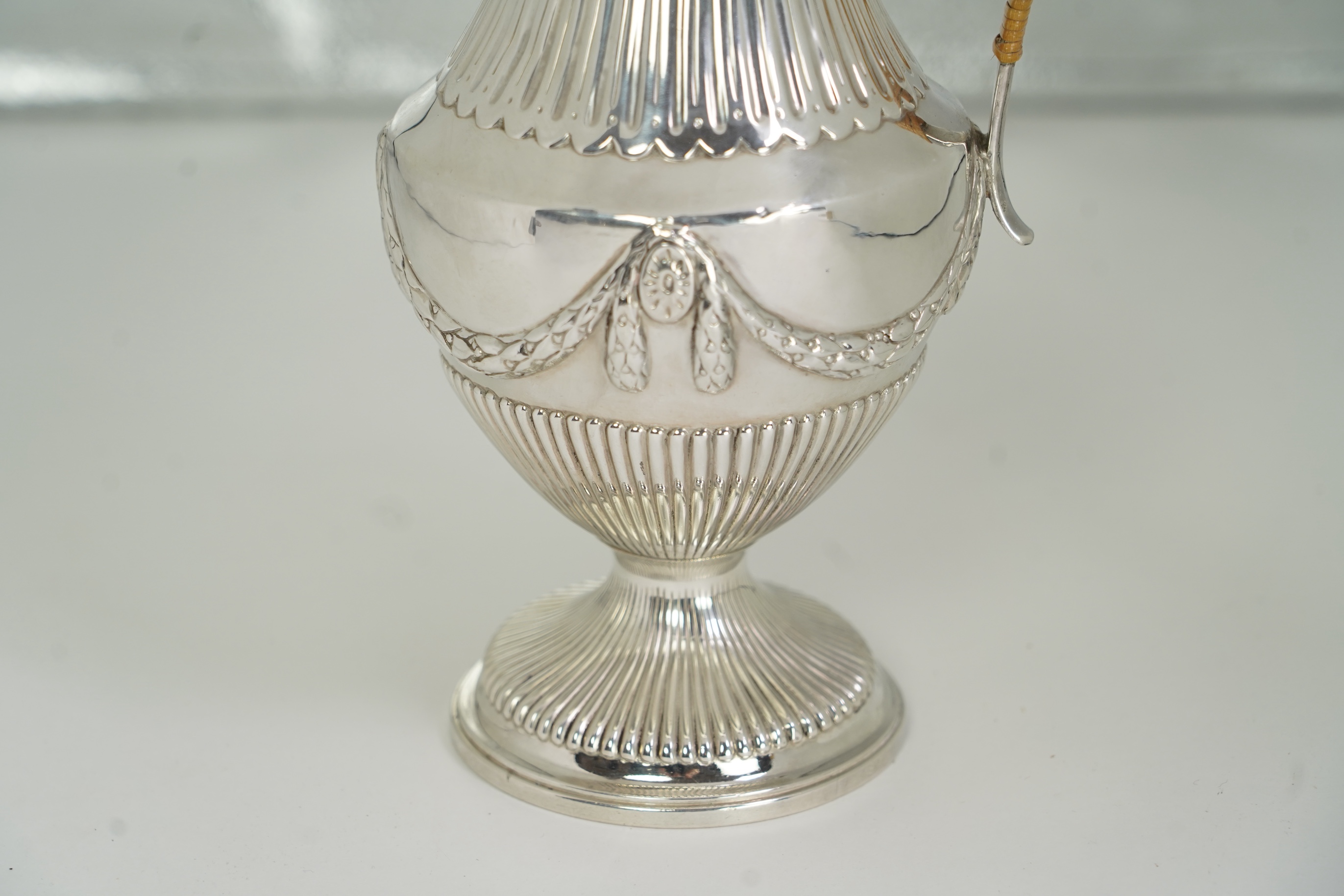 A George III neo-classical silver pedestal hot water pot, by Augustin Le Sage, engraved with the crest of The Right Reverend Robert Lowth, Bishop of London, (1710-1787)